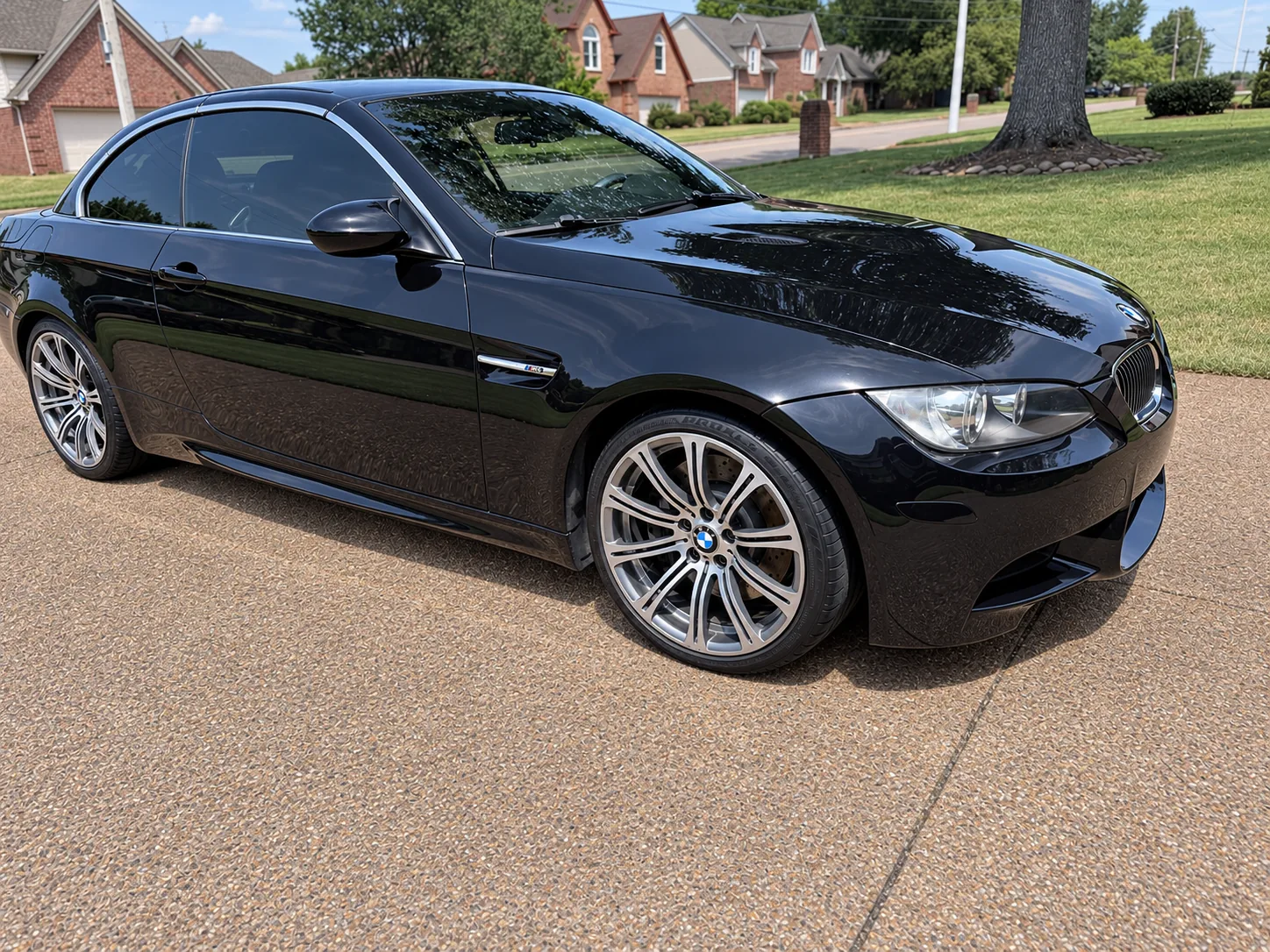 A black BMW M3 sedan with a ceramic-coated mirror finish on a driveway