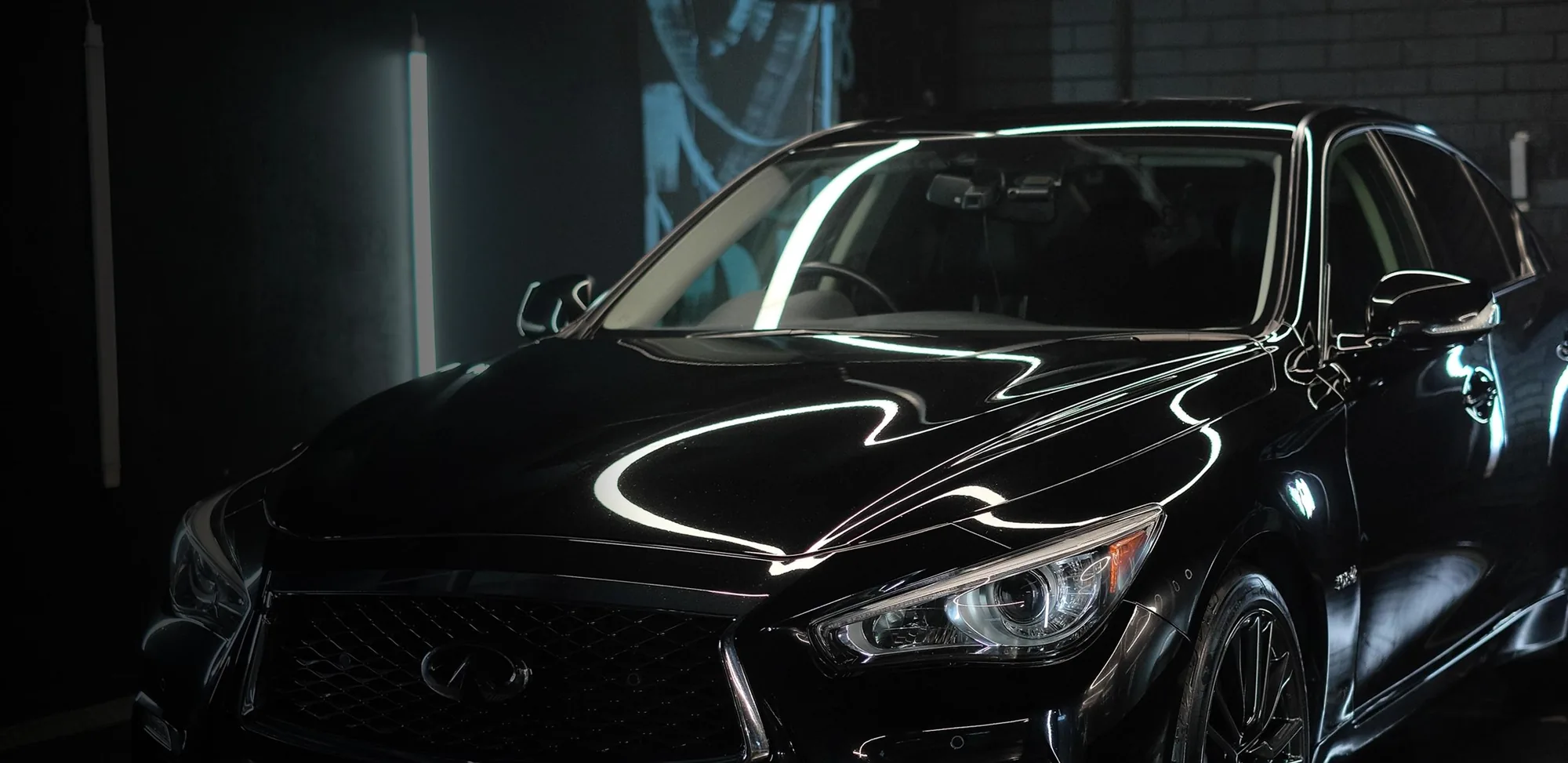 A black Infiniti under the lights of the TC Auto Solutions detailing bay